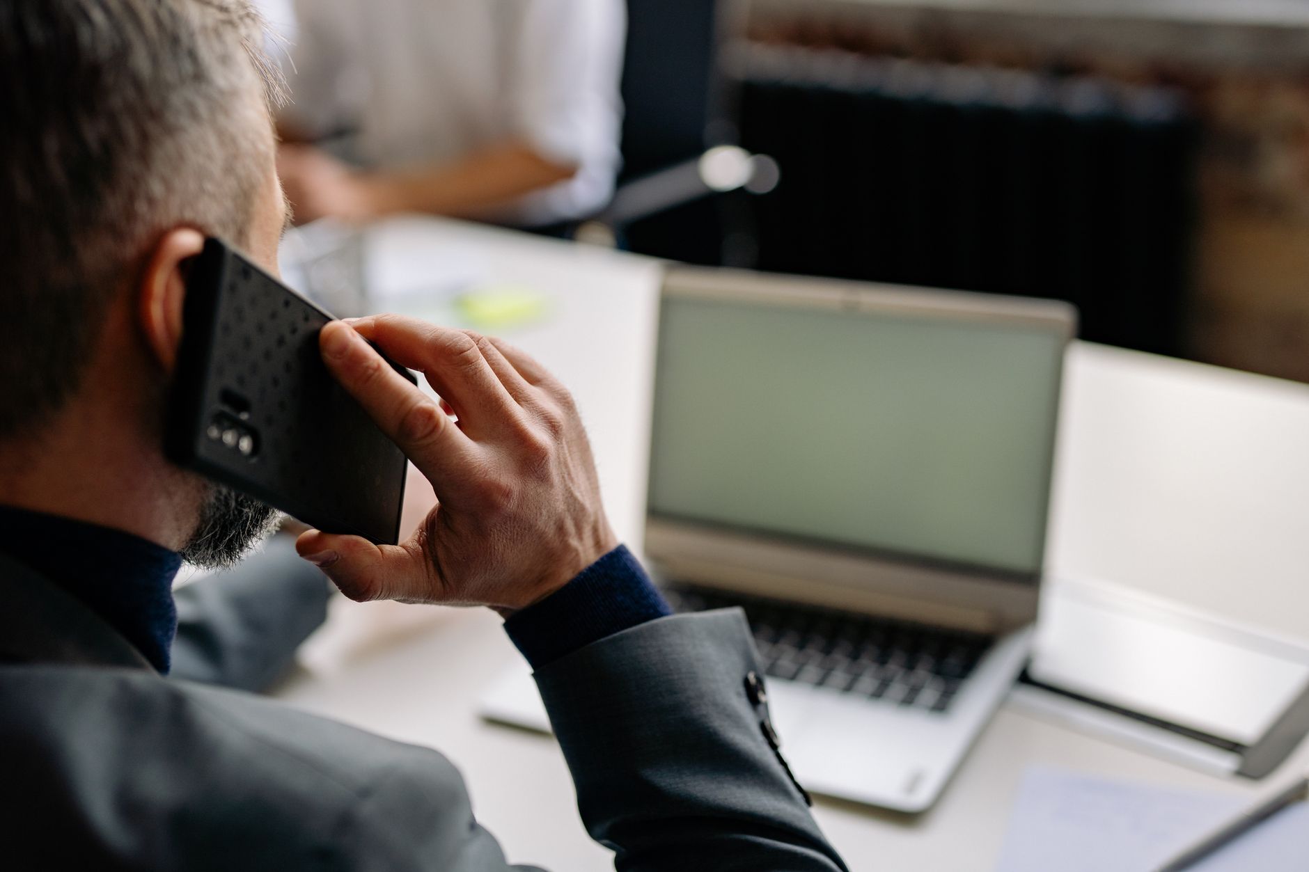 Homme au téléphone devant un ordinateur portable dans un bureau