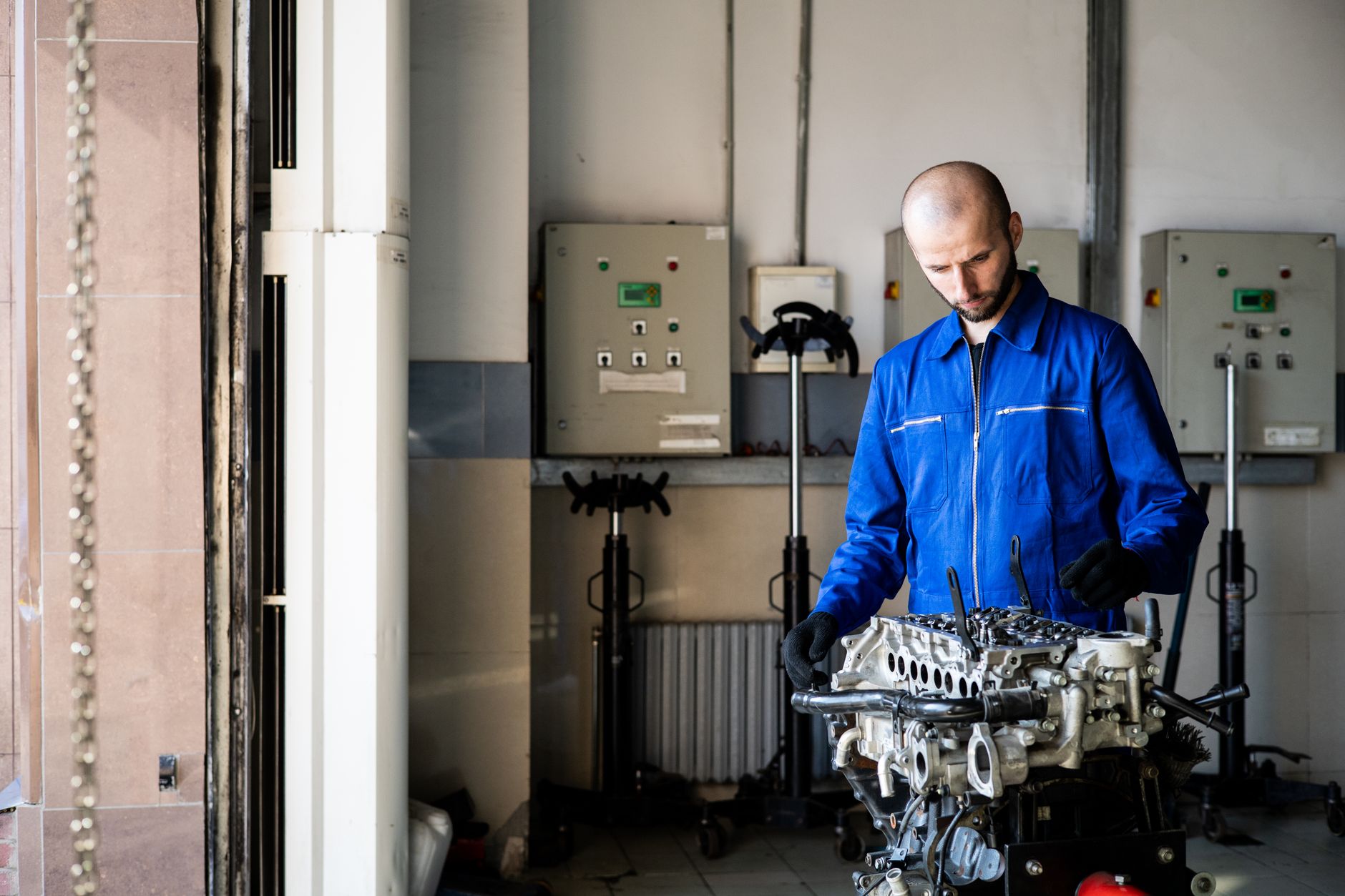 Mécanicien en combinaison bleue inspectant un moteur dans un atelier